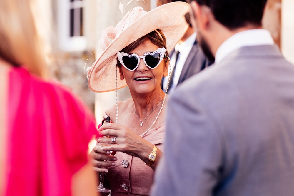 Cool wedding guest in sunglasses at drinks reception outside elmore court