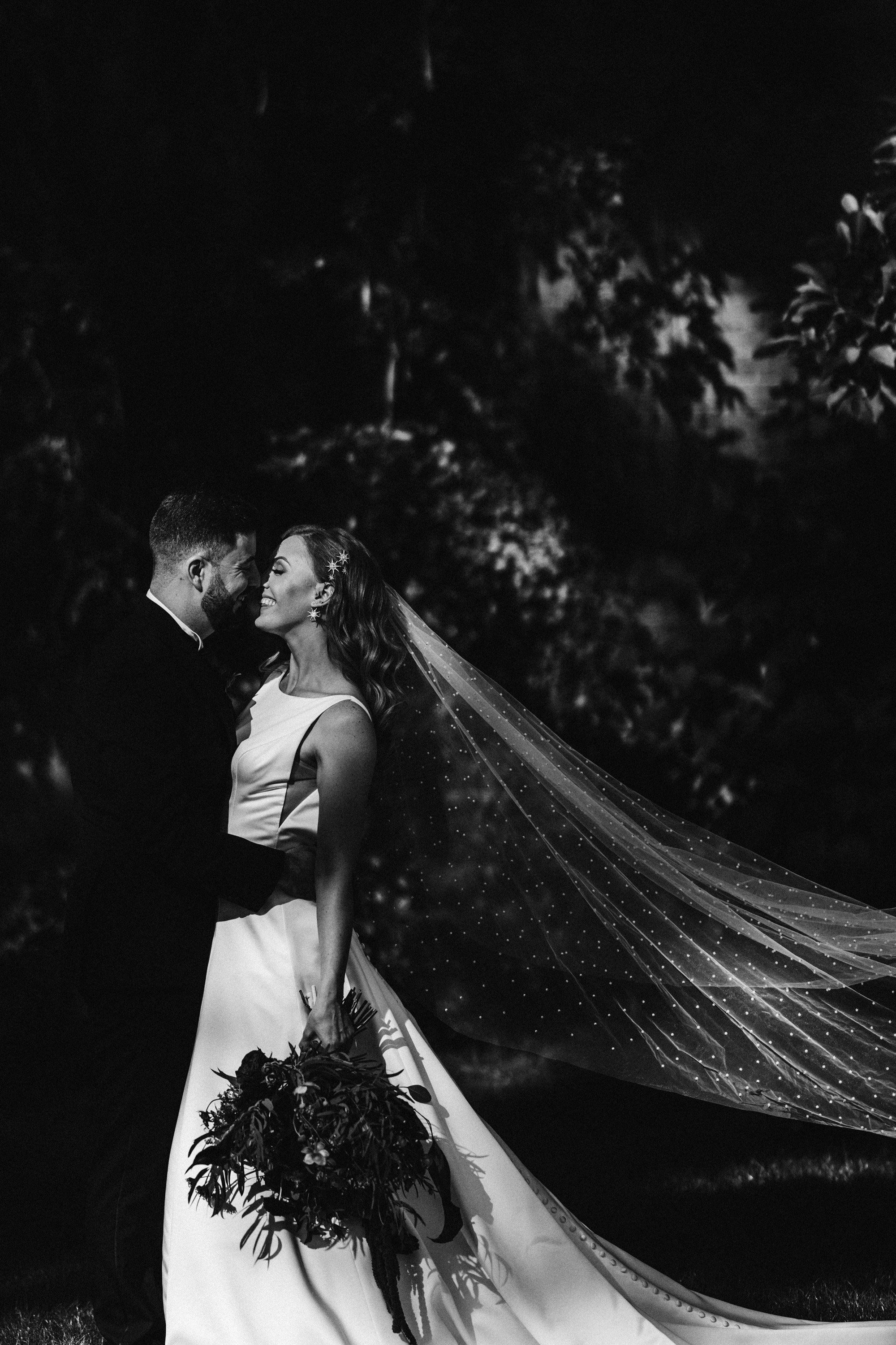 Dark and moody wedding photograph of a beautiful newlywed couple with bride wearing cathedral length veil in walled garden in Autumn at elmore court in Gloucester