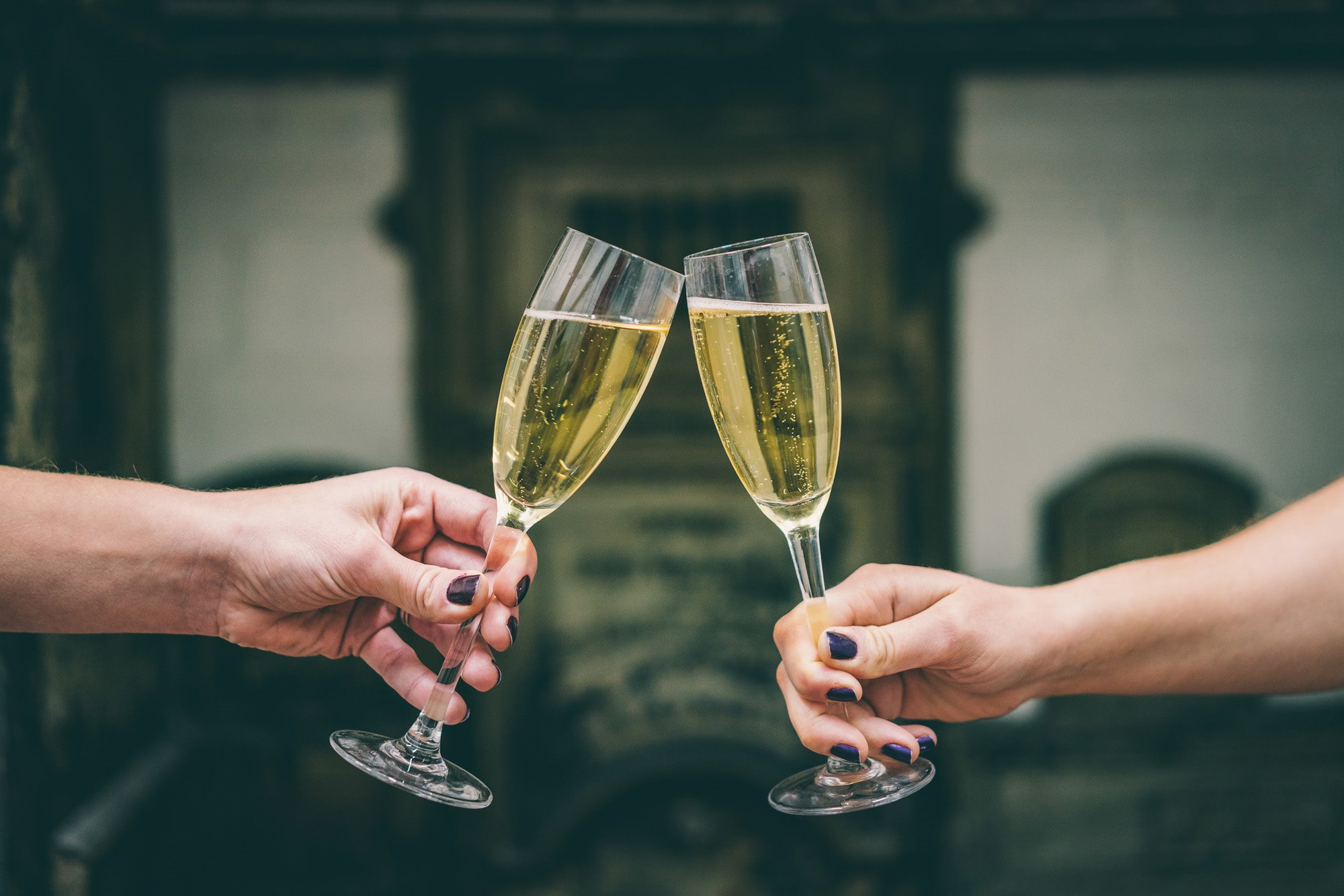 Champagne glass cheers by newlywed couple at Elmore Court wedding venue in the Cotswolds