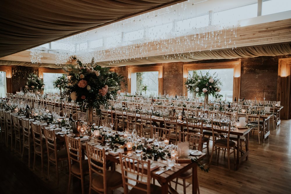 Boho wedding reception with long banquet tables candles and foliage in March