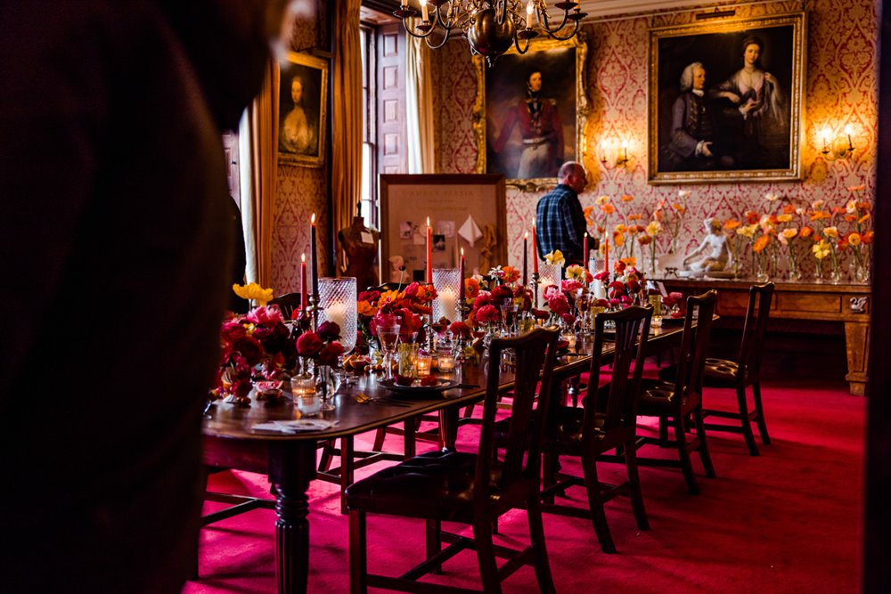 Hot pink and red wedding inspiration in the dining room at stately home wedding venue elmore court with paintings of ancestors and red carpet and wallpaper and antique furniture 