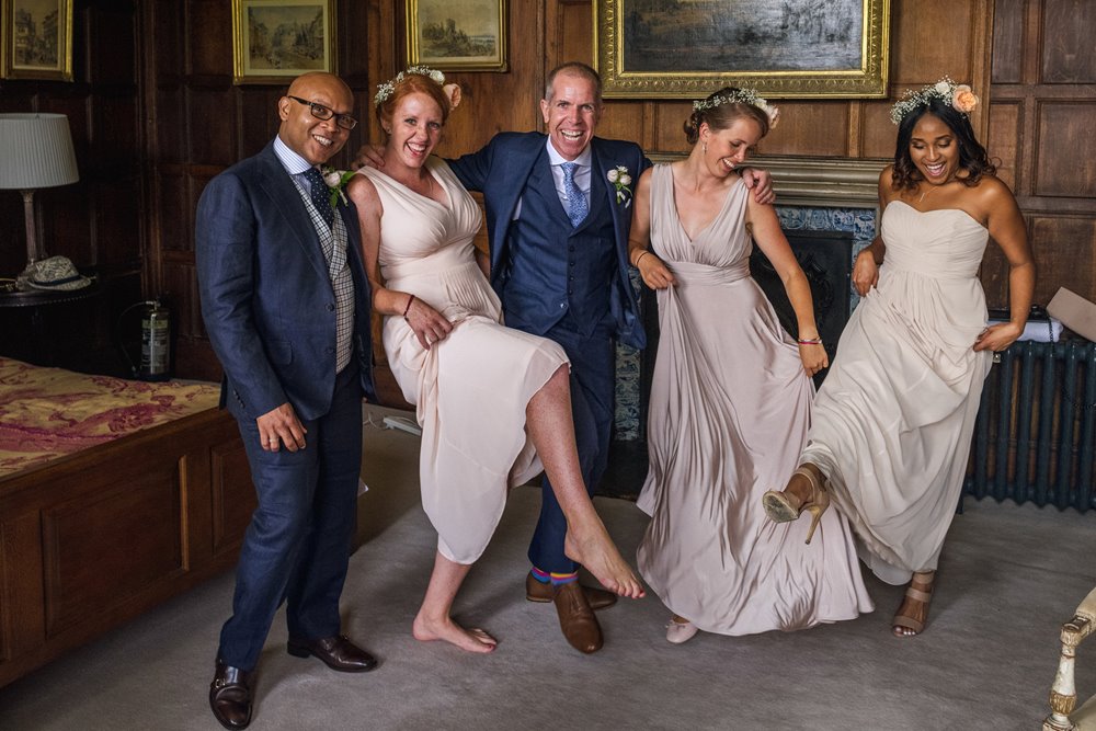 two grooms pose with their bridesmaids in historic house bedroom of elmore court