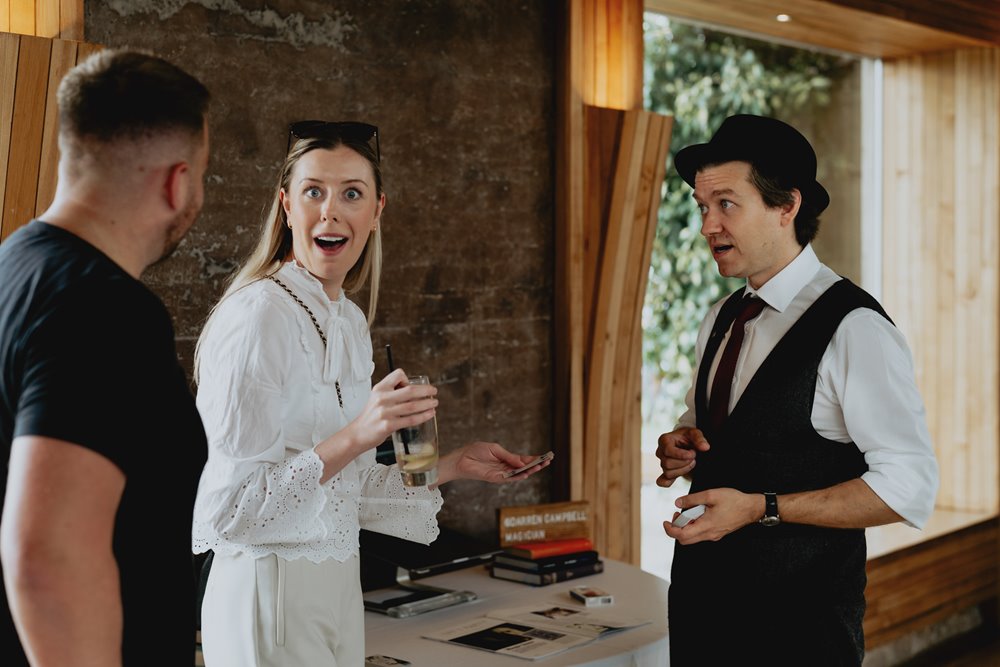 Wedding magician Darren Campbell showing off his tricks to amazed guests at wedding fair at elmore court