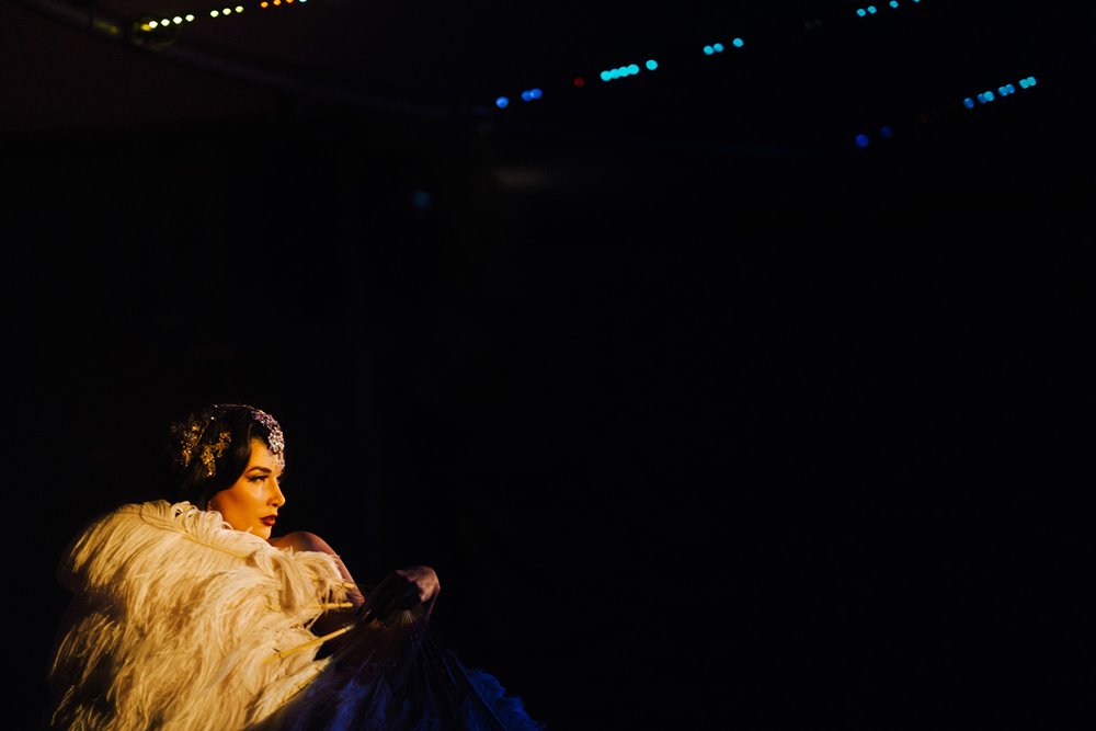 Burlesque star hidden behind feathered fan on stage at The Parrot Cage covid safe cabaret dinner & burlesque show