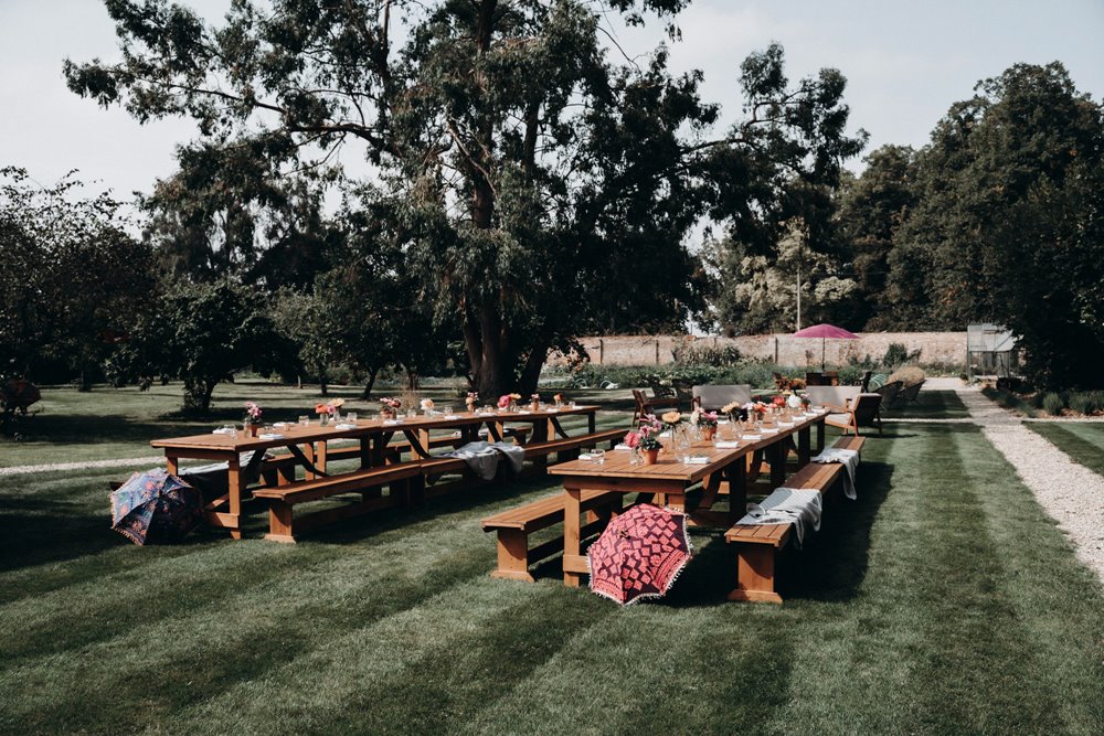 walled garden wedding with benches and indian parasols decor for an outdoor wedding at elmore court