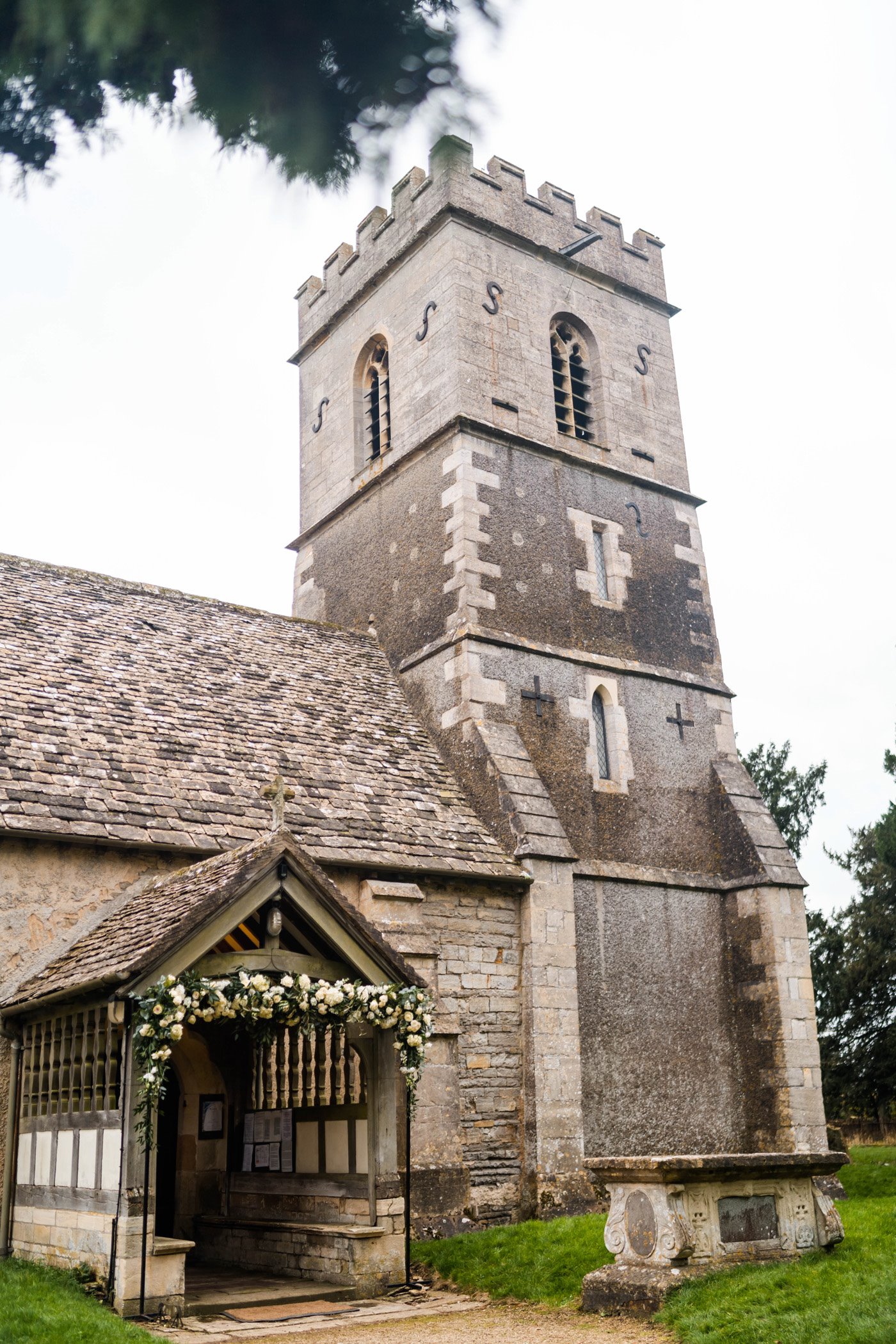 England's prettiest church is Elmore in Gloucestershire. Here is is with greenery and white flowers at entrance for a wedding