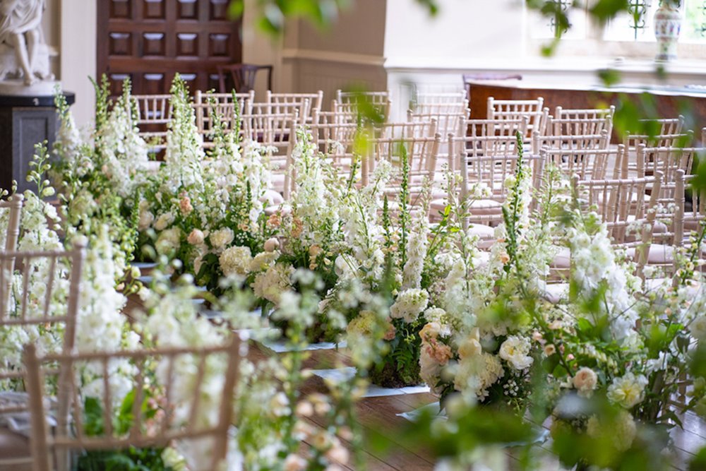 Floral aisle with tall green and white flowers for a spring wedding at elmore court