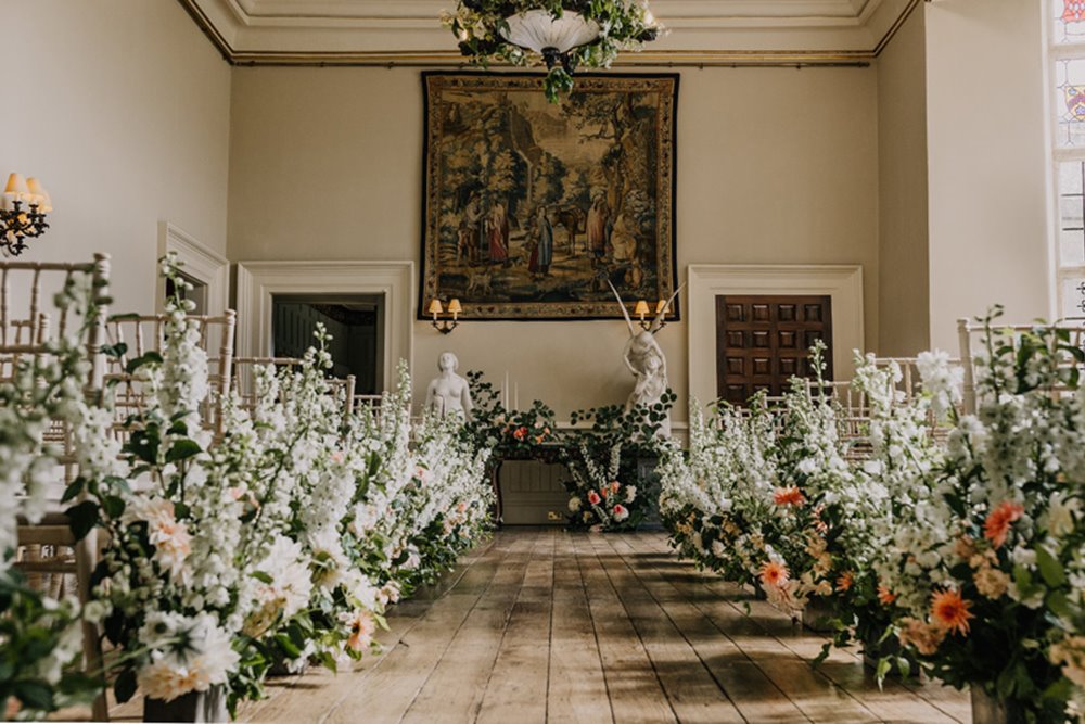 Tall white and green floral wedding aisle at stately home elmore court