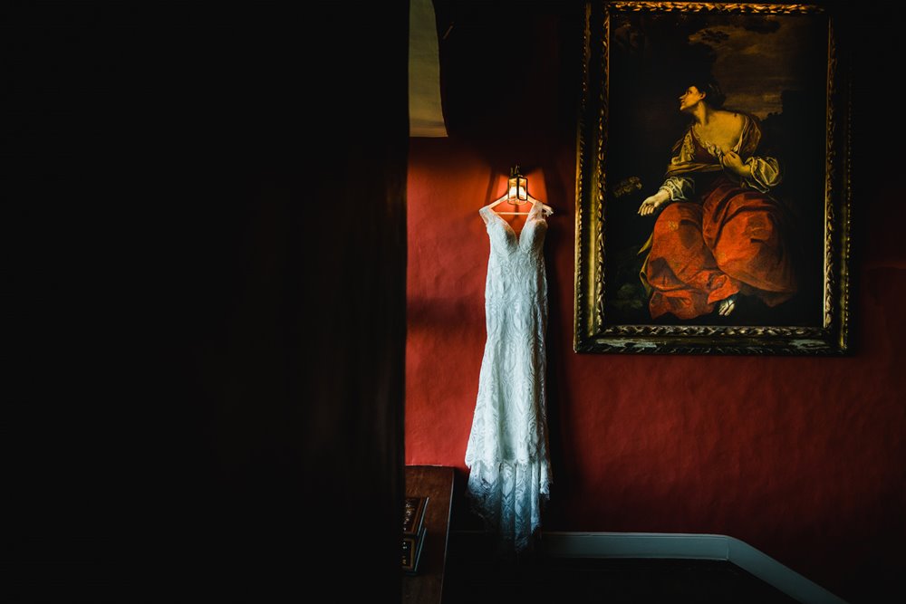 Lace wedding gown hanging in old manor house 