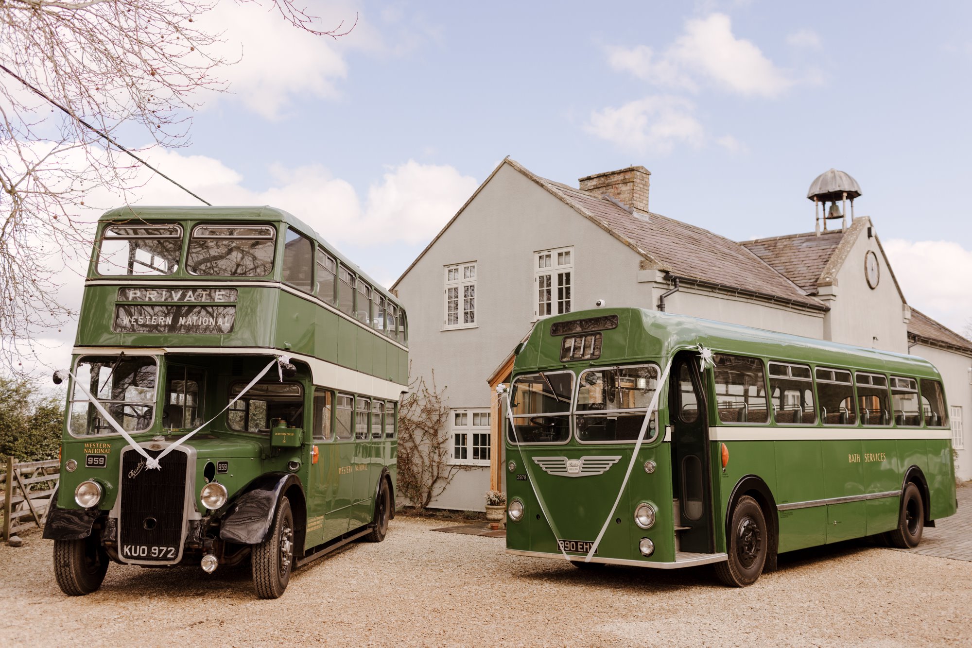 Vintage buses parked in front of the coach house at elmore court for a garden wedding