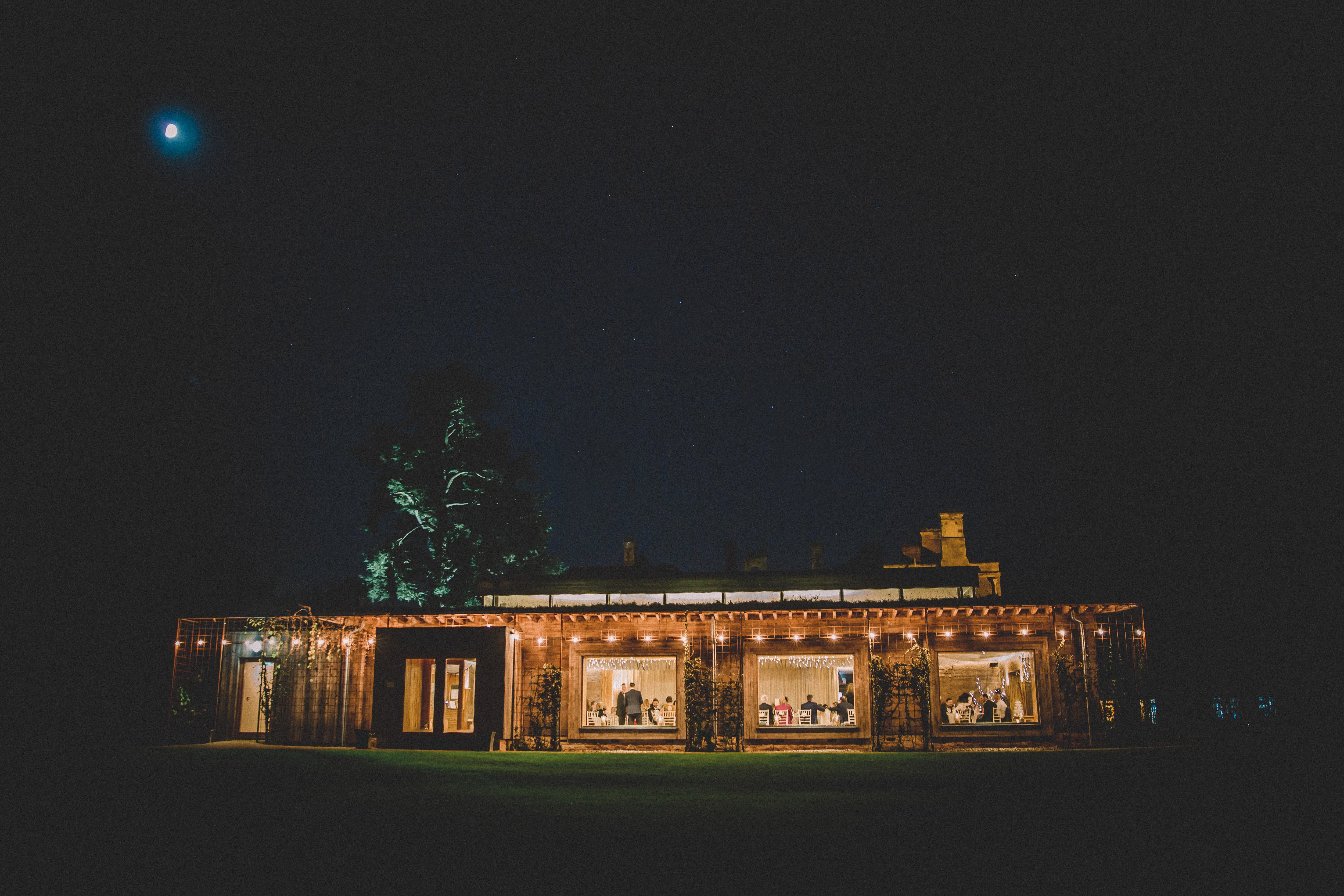 Eco wedding reception venue The Gillyflower glowing at night with festoon lights and warm light emitting from the windows