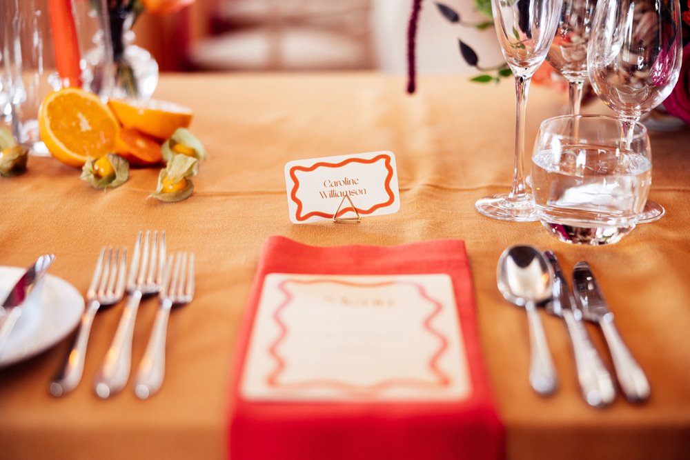 Clashing Colourful wedding theme. Orange tables with fruit at eco wedding venue in the cotswolds