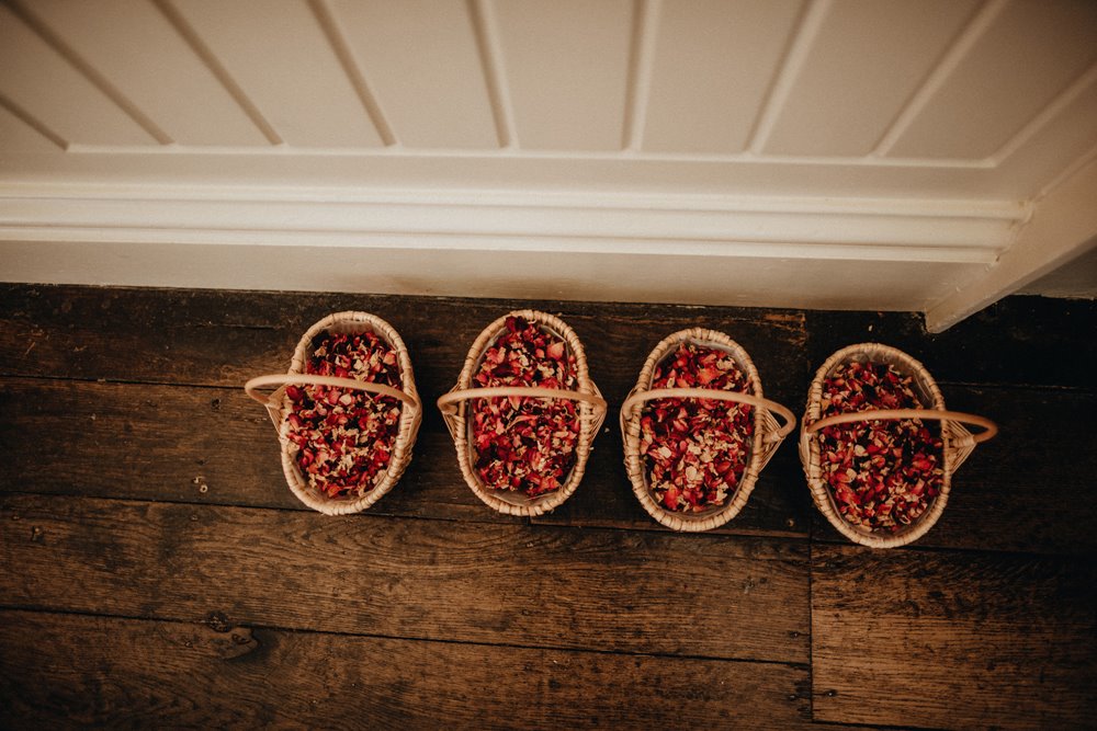 4 baskets of flower petal confetti, sitting on the wooden floor of a stately home and wedding venue