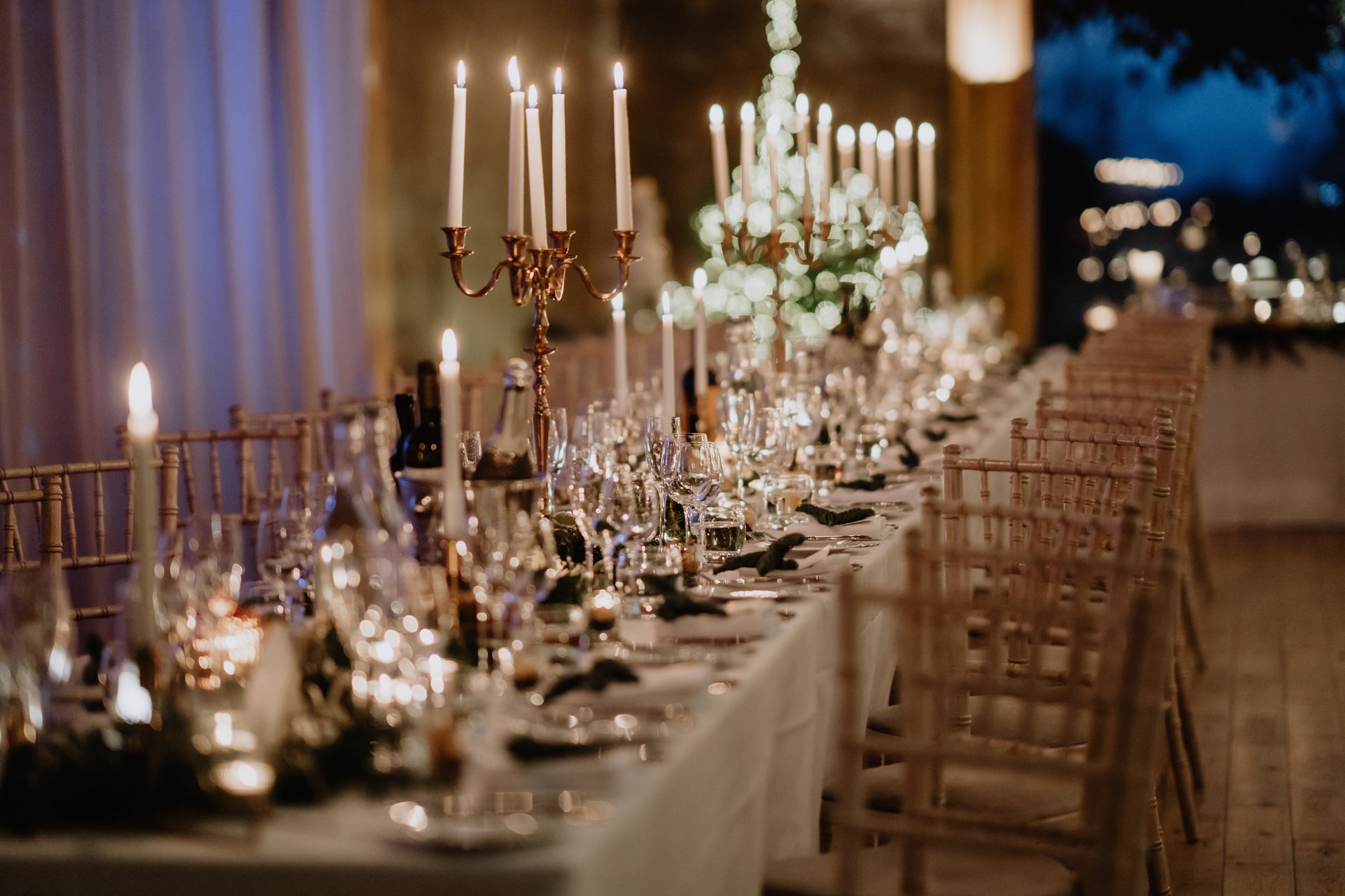 wedding reception tables styled with tall white candles in copper candelabras