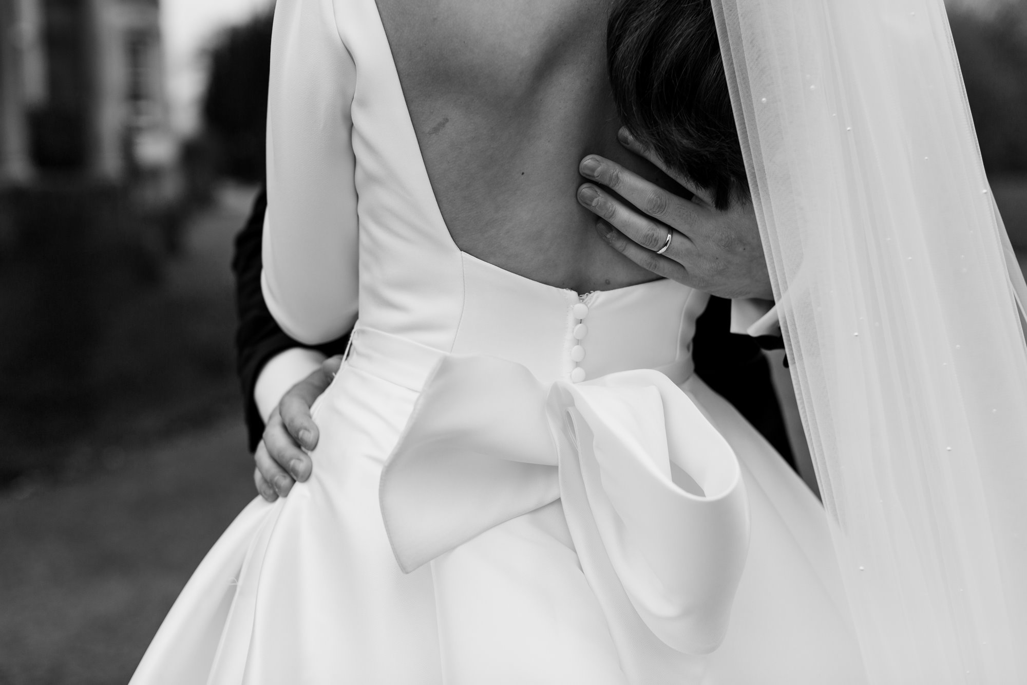 groom embracing bride in her lovely white bowed wedding dress
