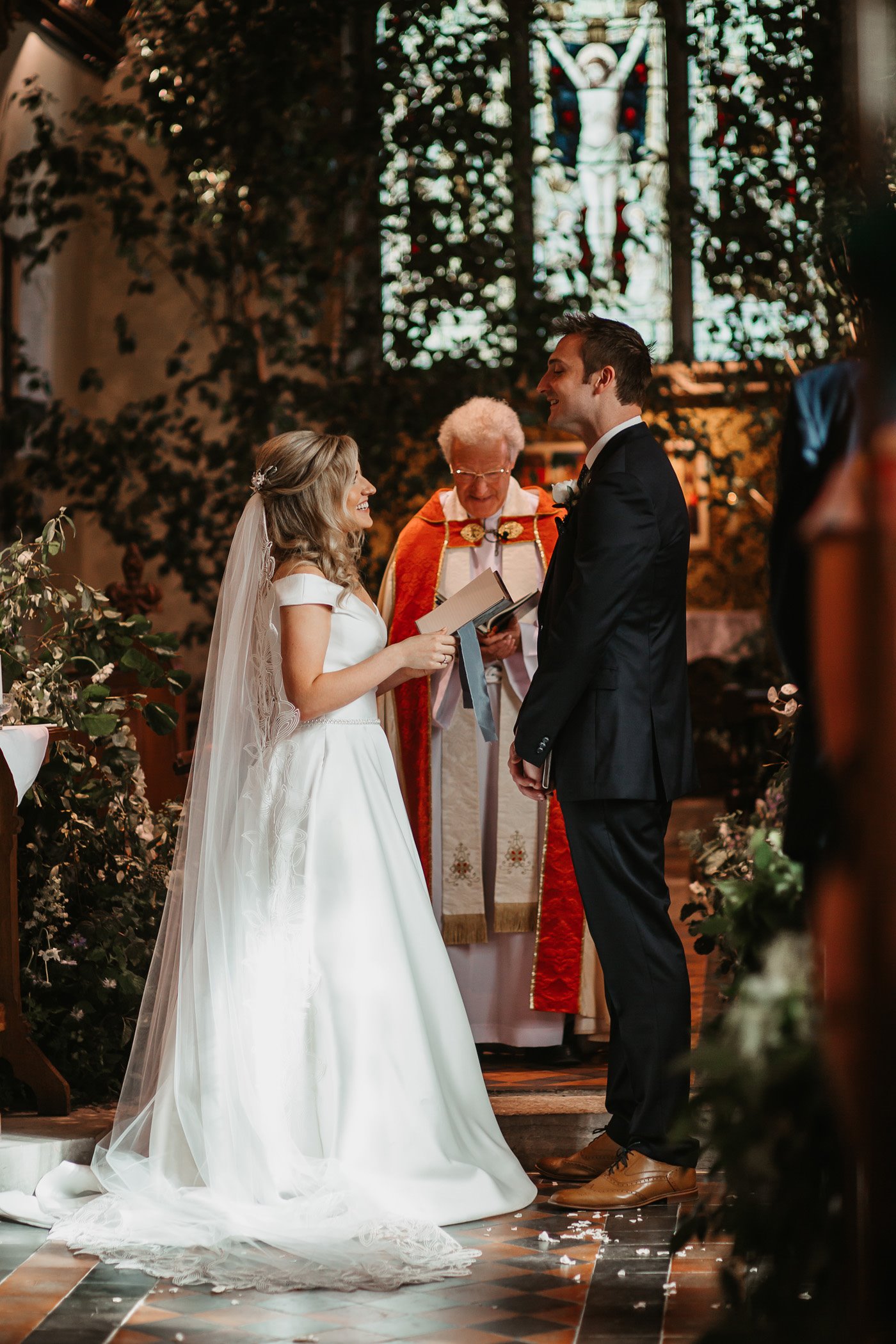 Religious ceremony in church Vicar behind couple who are smiling holding hands in church