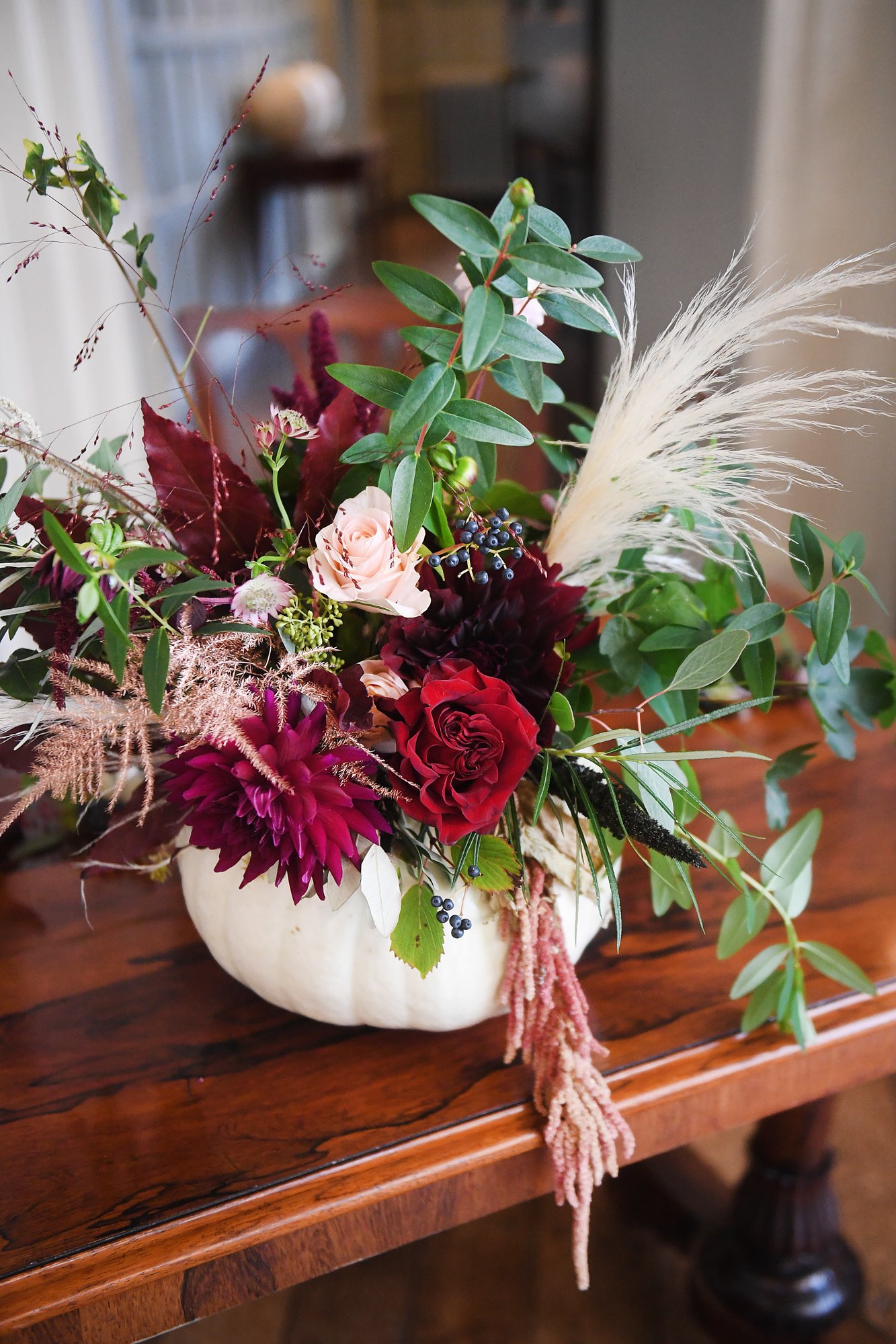 rich autumn wedding flowers in a white pumpkin for an autumn wedding theme