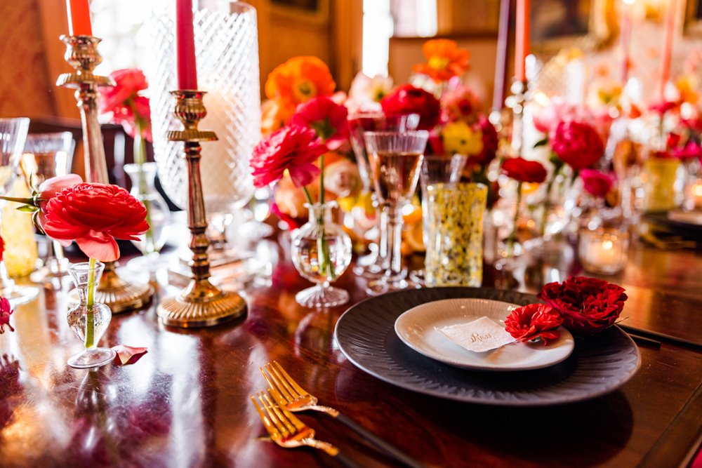 Bright red, pink and orange wedding flowers in dining room at elmore court wedding venue in gloucestershire