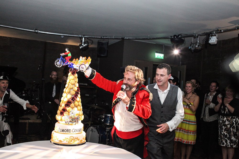 Anselm Guise and Hamish Geurrini of rabbit hole glastonbury with huge tower cake and toy car funny festival entertainment at launch party of wedding venue