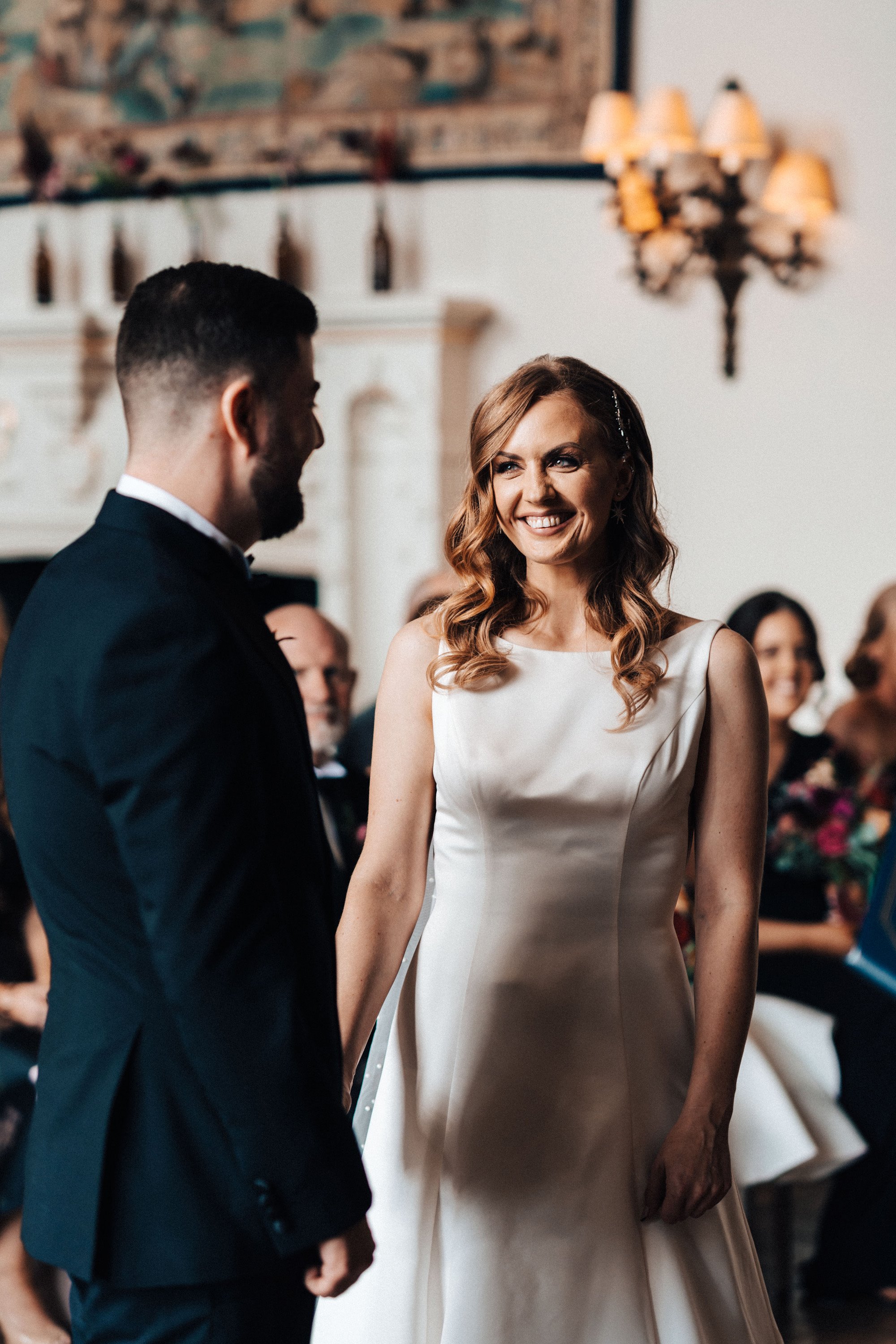 bride smiles at groom at the end of the aisle in beautiful autumnal wedding ceremony in a stately home in gloucester