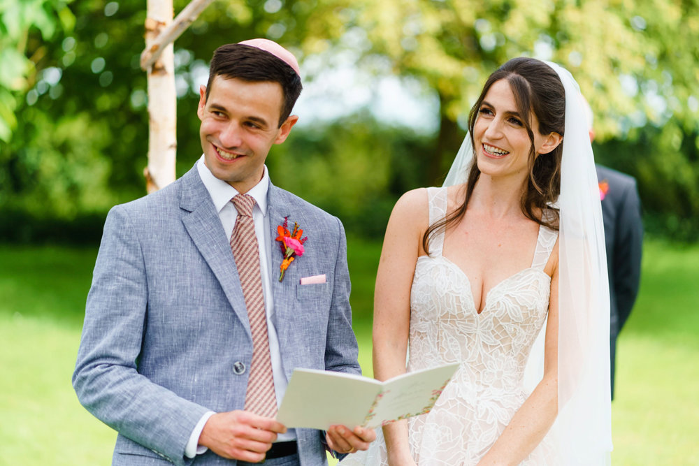 Jewish bride and groom looking beautiful in wedding outfits under chuppah
