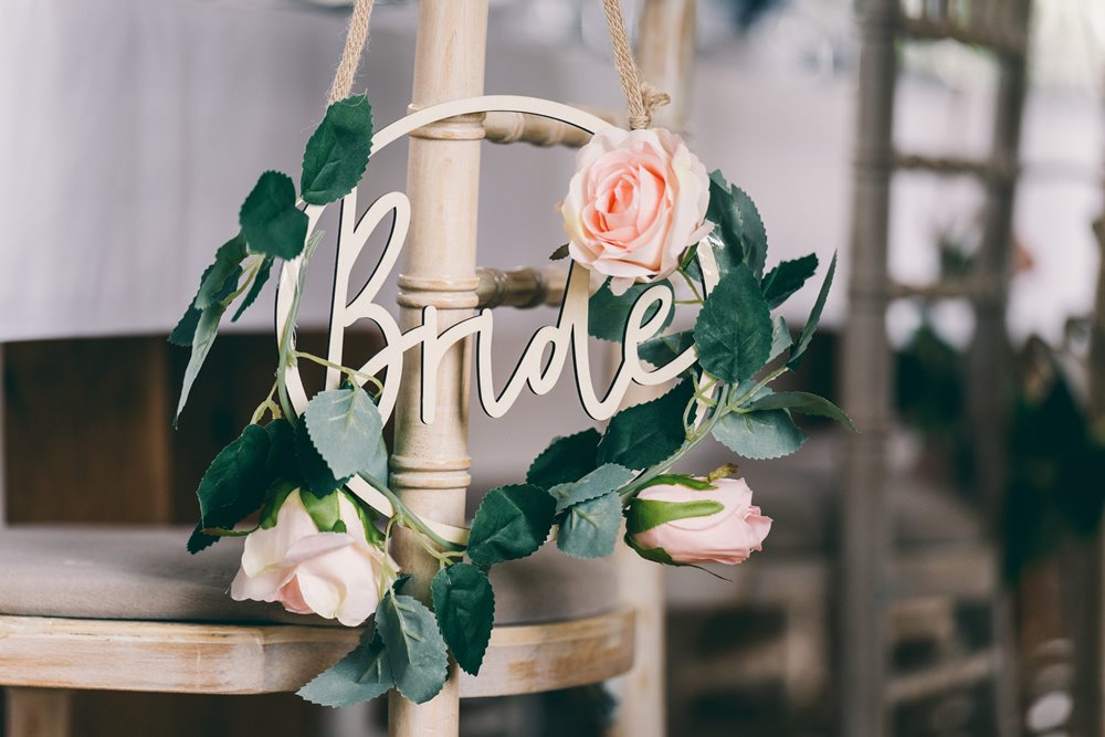 Pink roses decorating a sign with bride written on it showing where the bride sits at her romantic wedding reception
