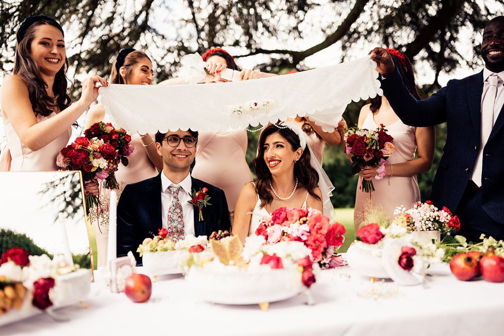 Traditional persian wedding ceremony with Sofreh ye Aghd with beautiful pink and red details and sugar ceremony