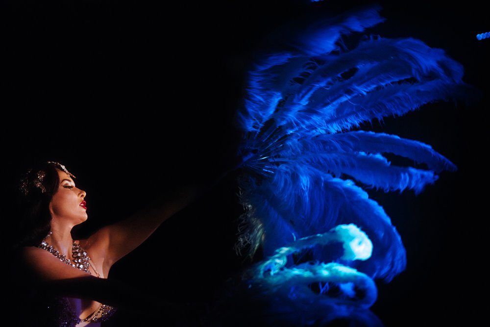 Burlesque siren Missy fatale waving blue feathered fan at cabaret dinner show in the cotswolds