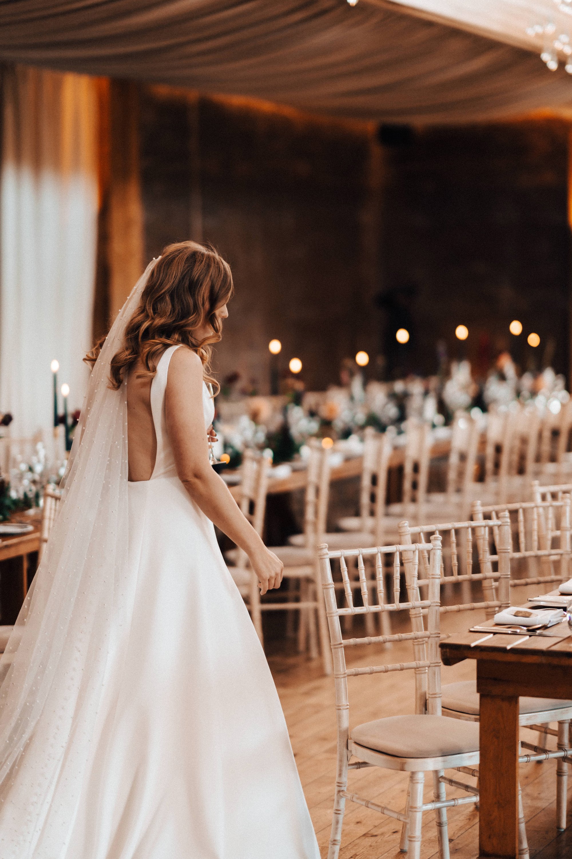 Bride sees her magical autumn wedding reception for the first time with black candles and flowers in october at sustainable wedding venue elmore court
