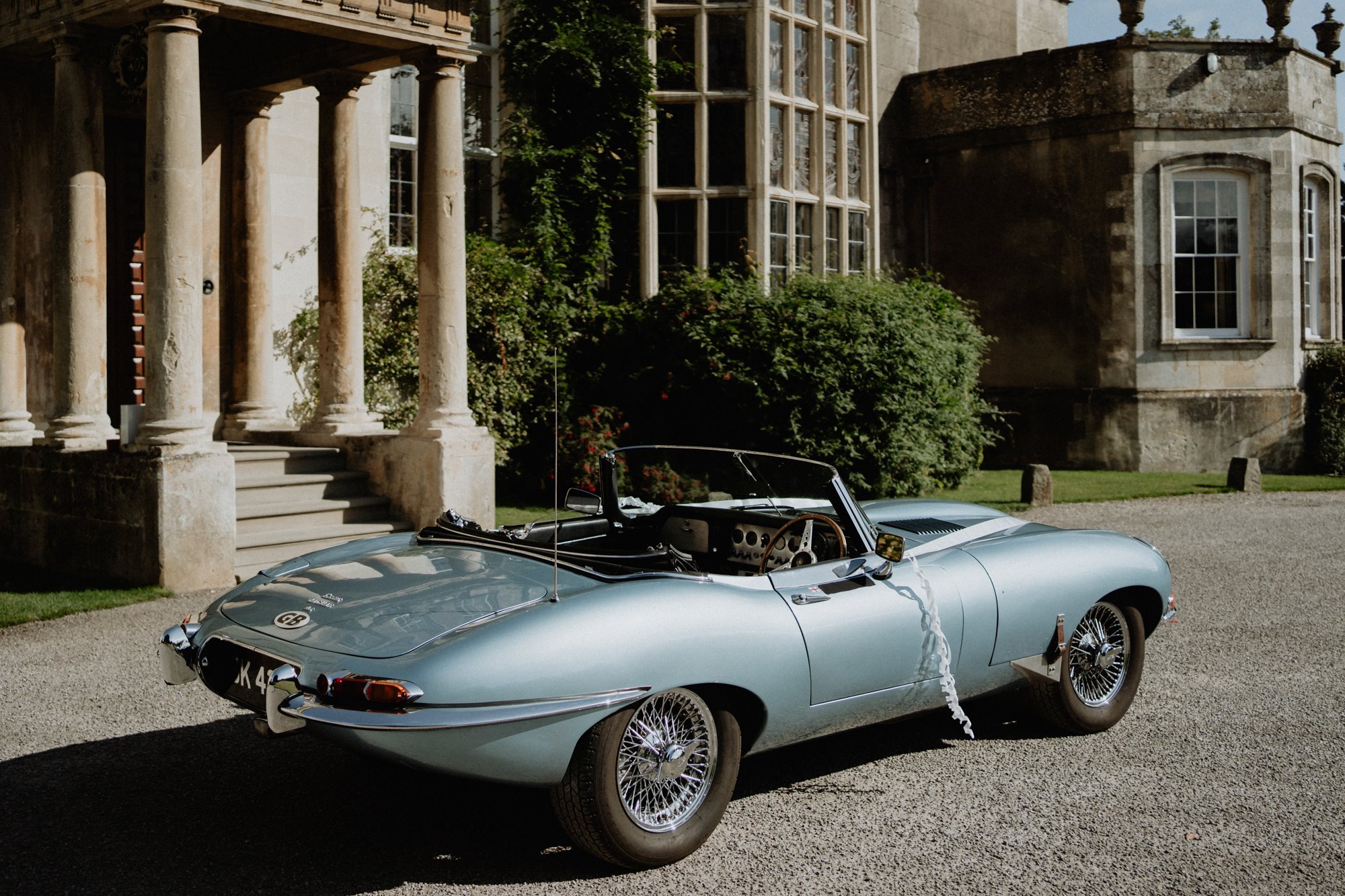 Vintage car with ribbon parked in front of mansion house elmore court for a garden party wedding