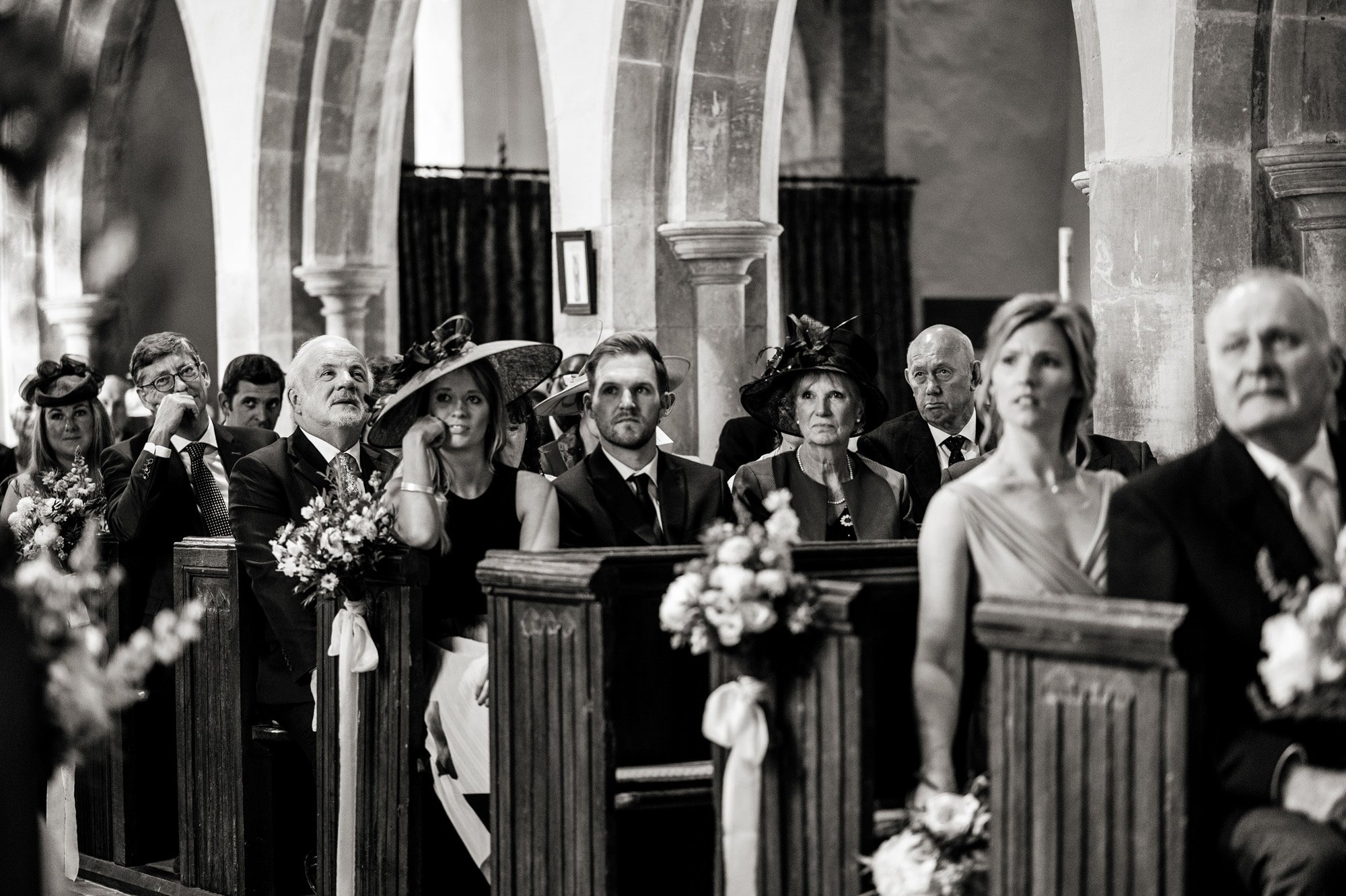 Black and white photo os Wedding guests in pews at a church wedding at Elmore