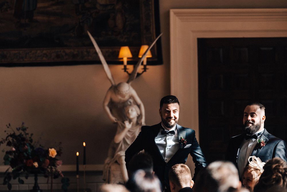 autumn light hits the groom waiting for the bride in beautiful stately home in the english countryside