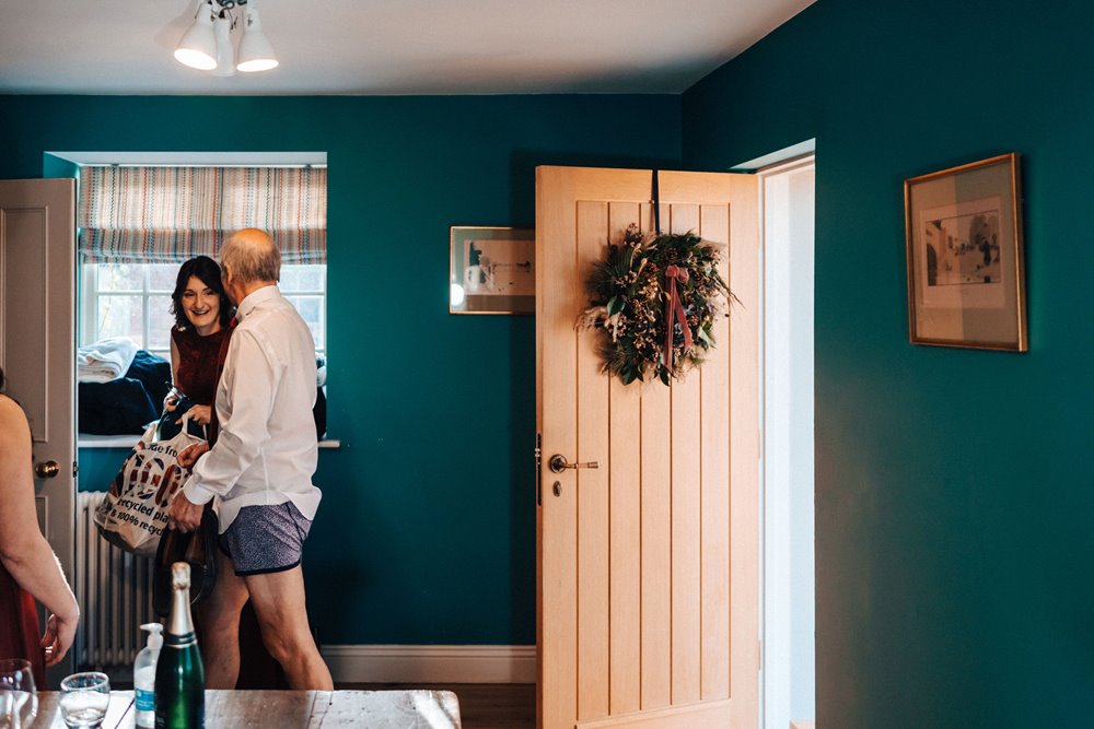 funny wedding photo of father of bride in boxer shorts with christmas wreath on the door