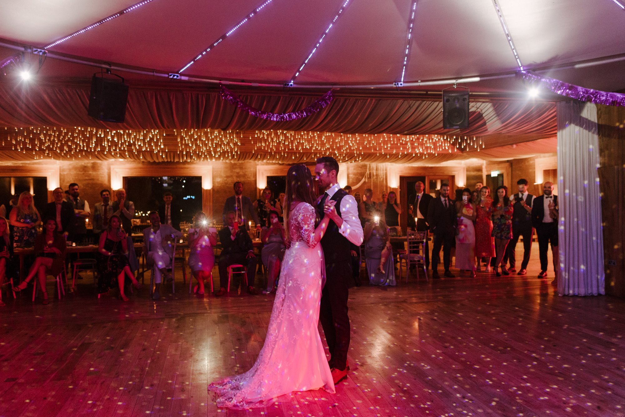 Boho bride and groom have their First dance in an eco wedding venue with beautiful dance floor and festival sound system