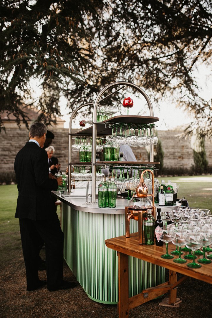 Outdoor gin bar in beautiful green ombre with copper details stationed under the cedar tree for a cool outdoor wedding reception at Elmore Court