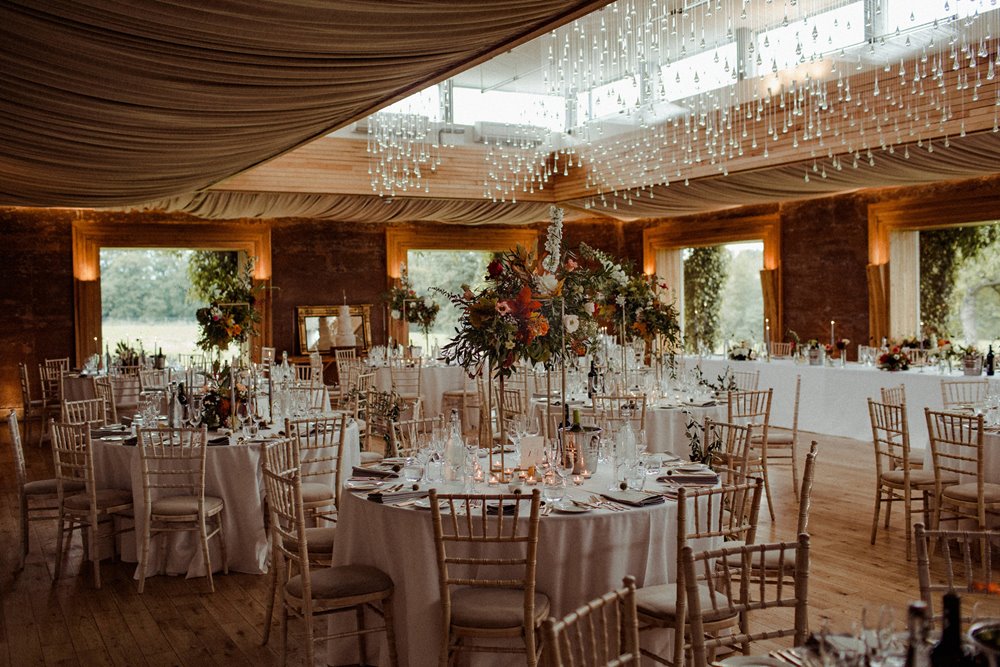 Autumnal wedding reception with big centre flowers on round tables in an eco reception venue in Gloucestershire