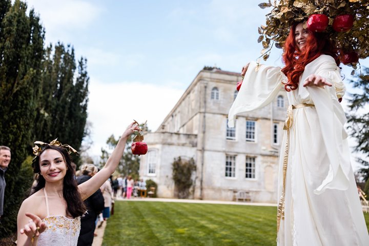 Festival walkabout performers on stilts and handing love notes in apples at unusual wedding venue elmore court in Gloucestershire for a wild wedding fair in 2022