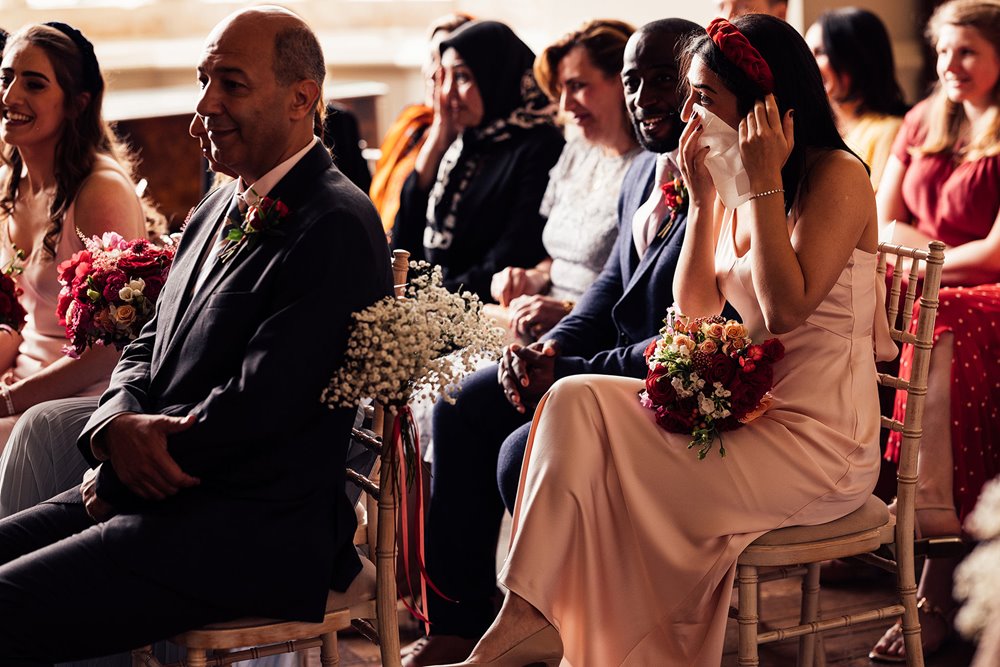 Crying bridesmaid wipes tears at wedding ceremony in the cotswolds