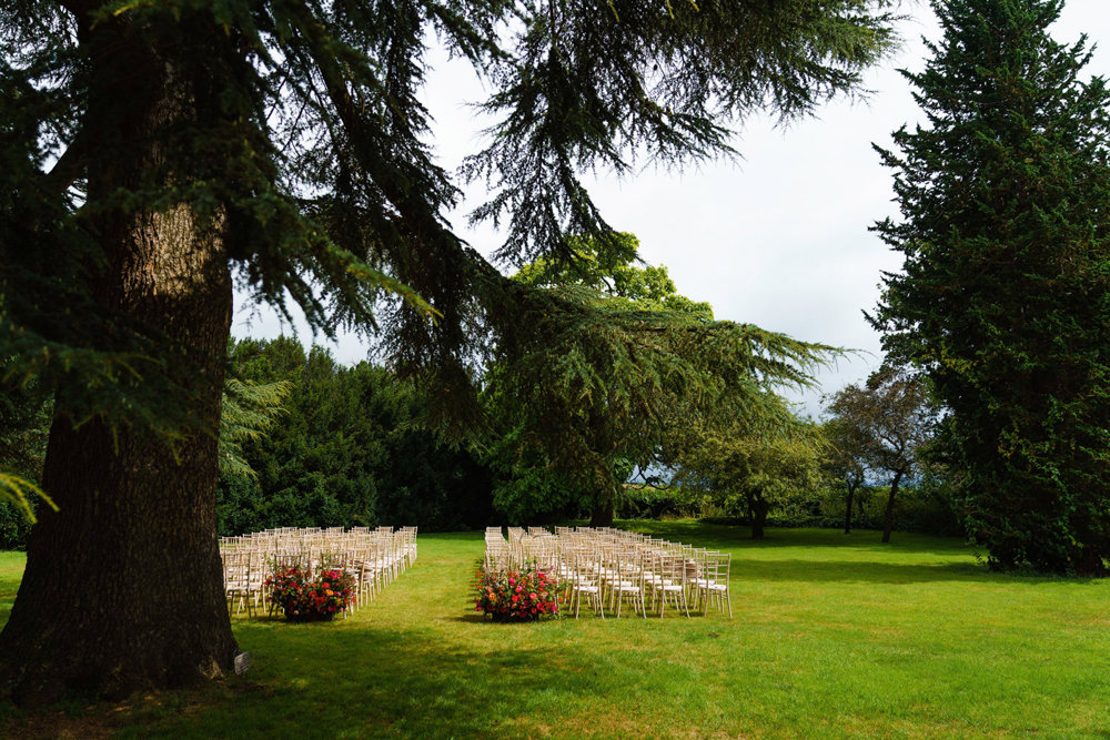 outdoor wedding ceremony setting up with pink flowers and chairs on the lawn