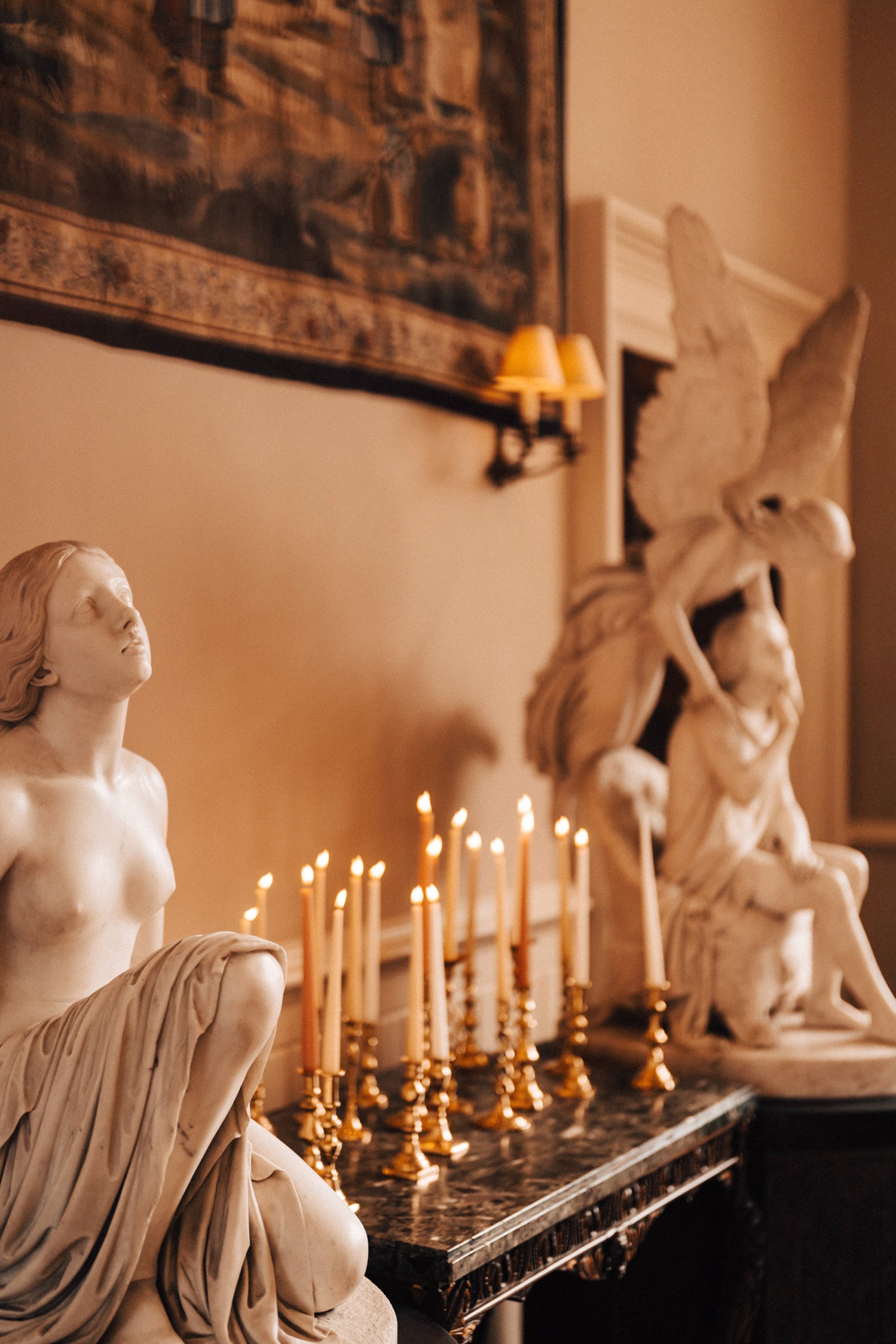 Beautifully warm candles glowing next to marble statues at an Elmore court wedding