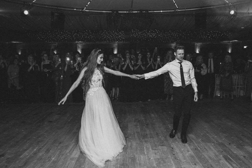 Modern boho Bride and groom hold hands at first dance on the dance floor in the gillyflower at elmore court
