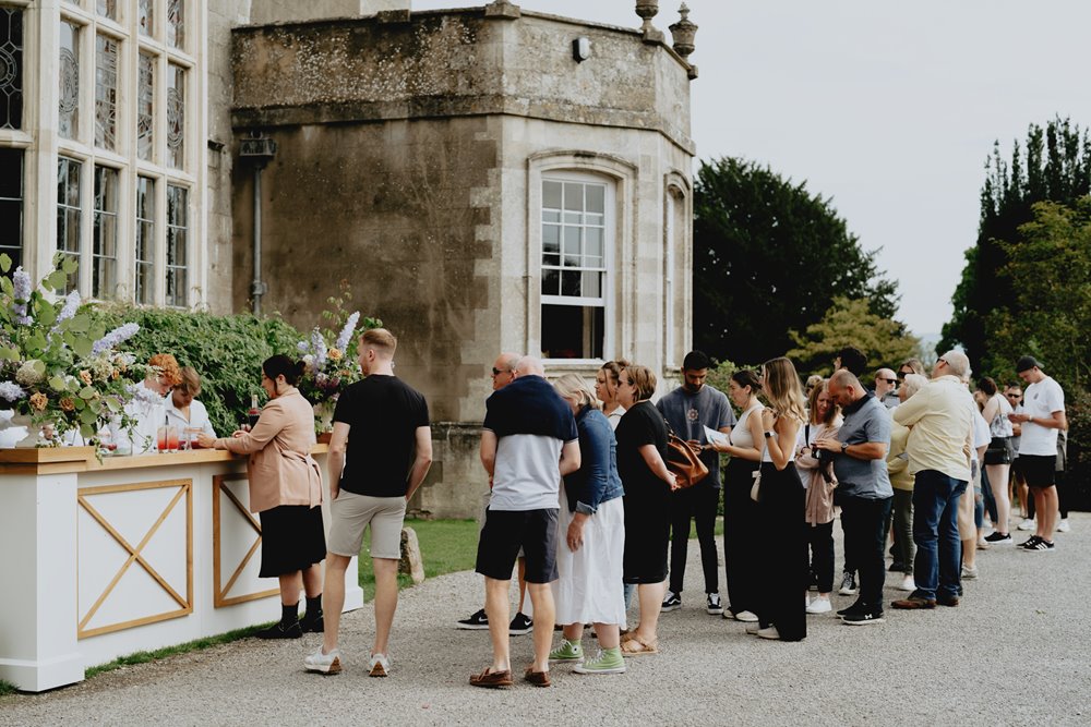 Guests queue for climate positive cocktails at sustainable wedding venue elmore court in Gloucester