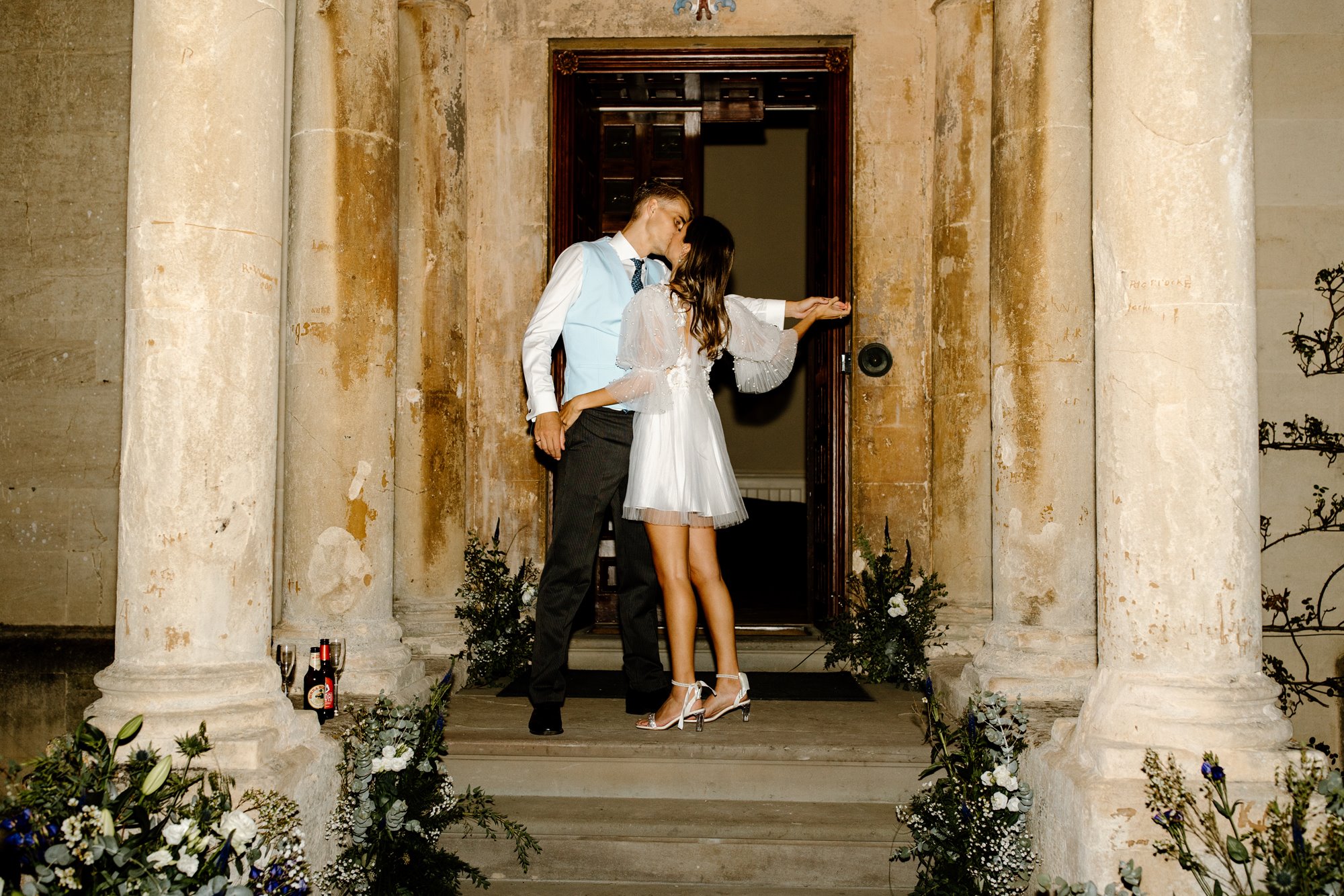 Newly wed couple kissing on the porch of a cotswold stately home in Gloucestershire