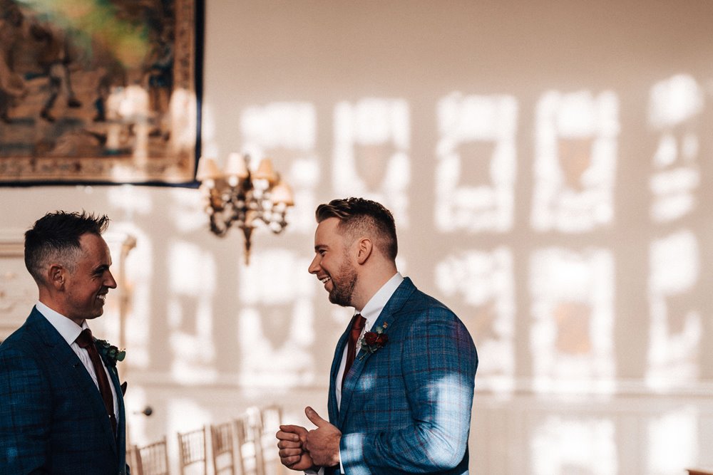 groomsmen in beautiful stained glass reflection at manor house wedding venue