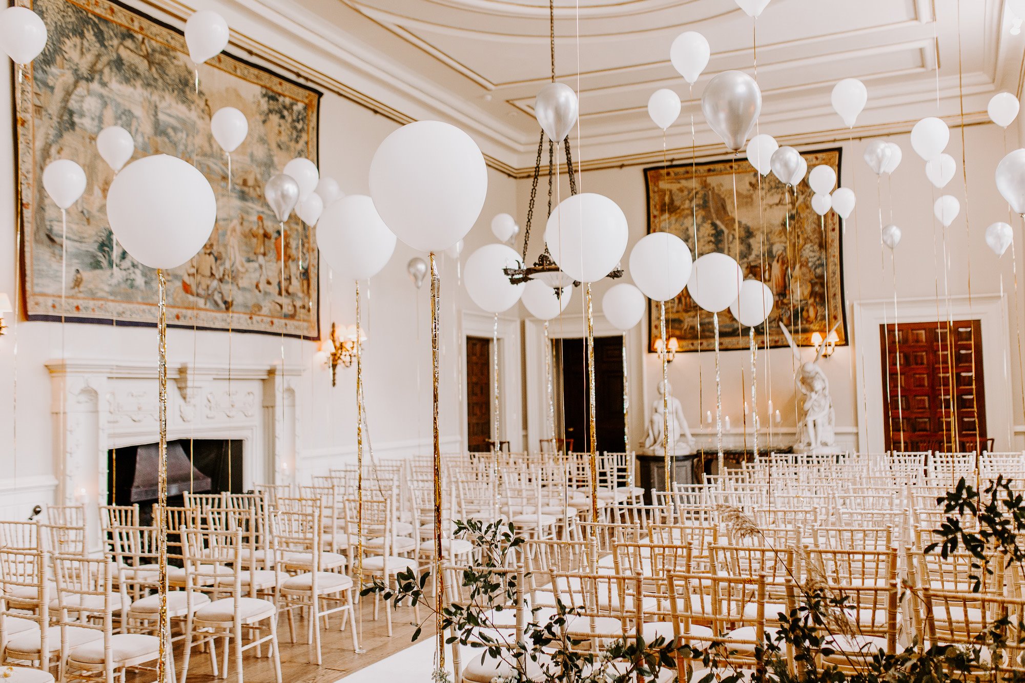 Pearlescent white and silver balloons decorating stately home hall wedding ceremony look like pearls on strings