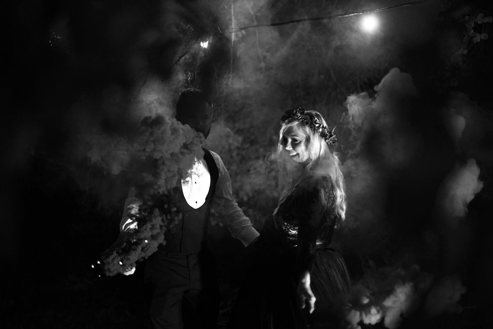 Moody photos of bride in black wedding dress with smoke bombs for halloween wedding