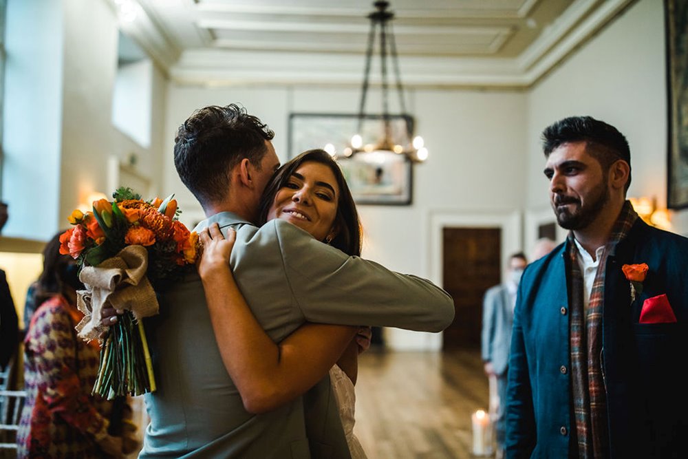 Happy hug bride and groom embrace at the end of the aisle at their micro wedding ceremony