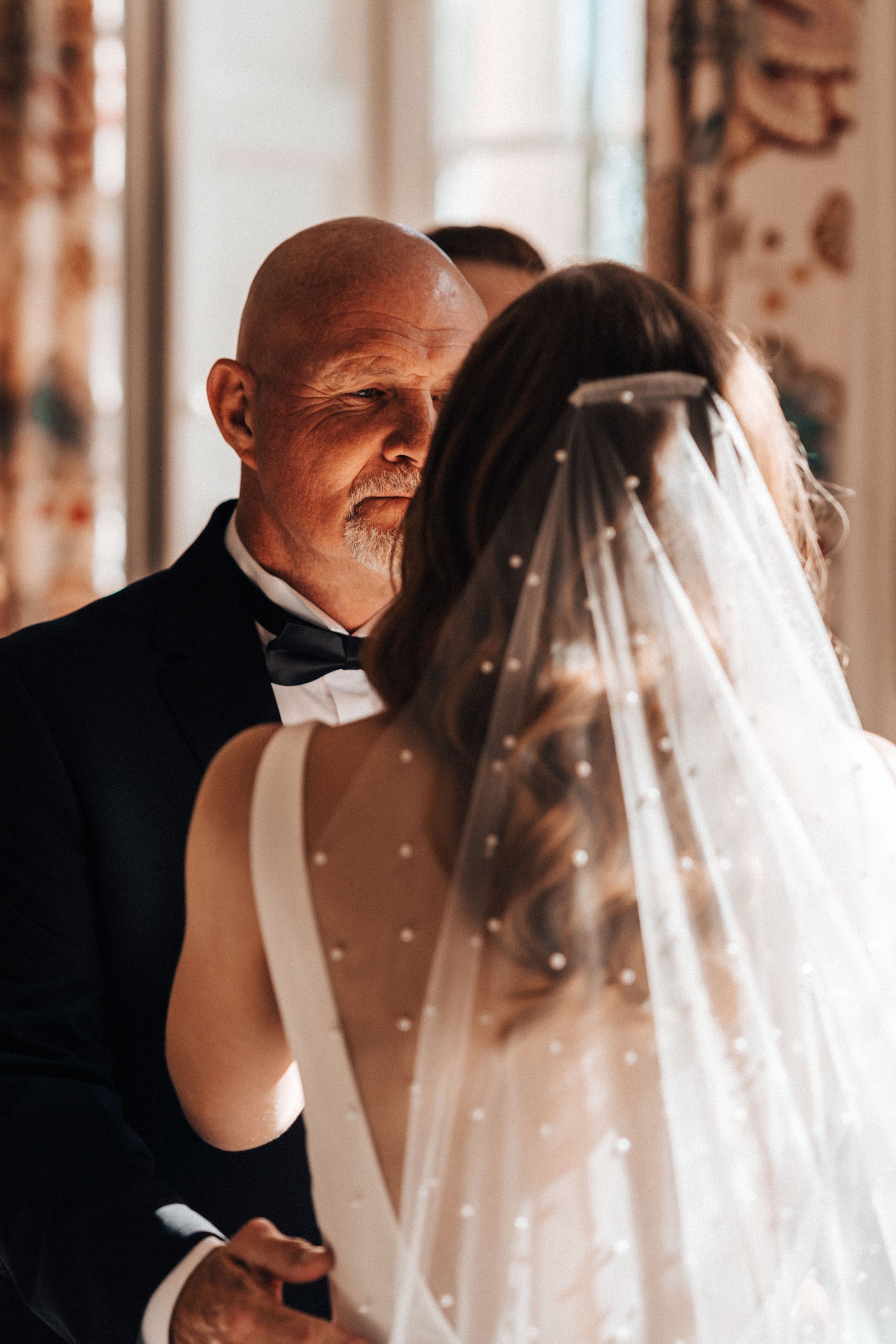 First look father of the bride wearing long veil with pearls on an autumn wedding morning in the cotswolds