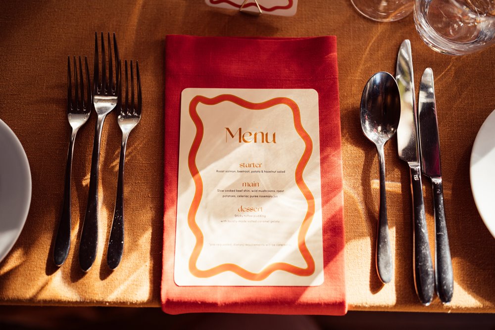 Colourful red table setting on orange table for fun retro wedding in Gloucestershire 