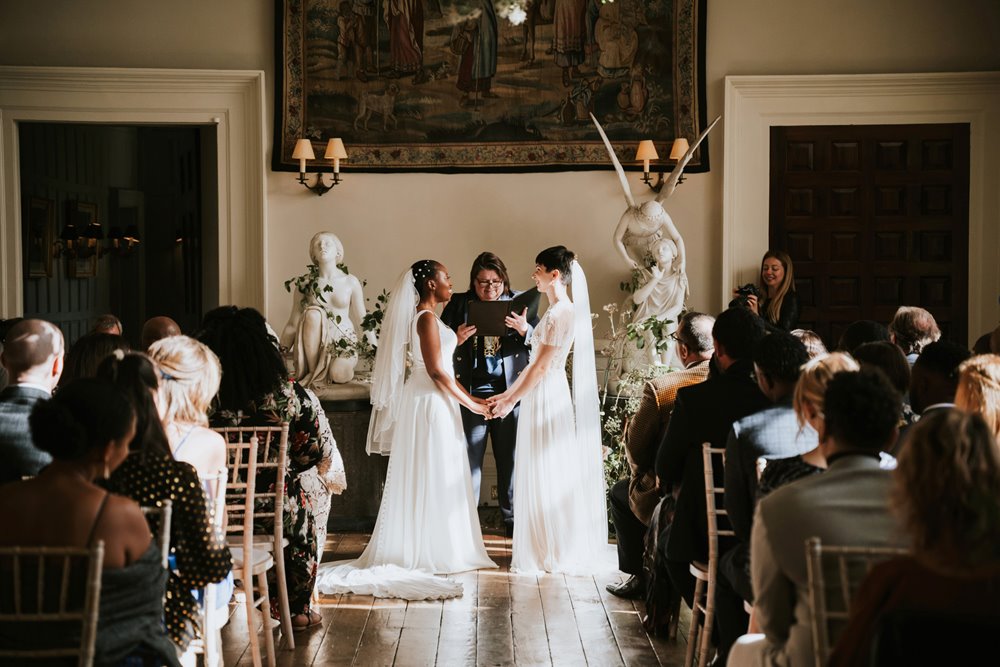 Two brides look ethereal in white wedding dresses and veils in Magical same sex wedding ceremony in beautiful stately home hall